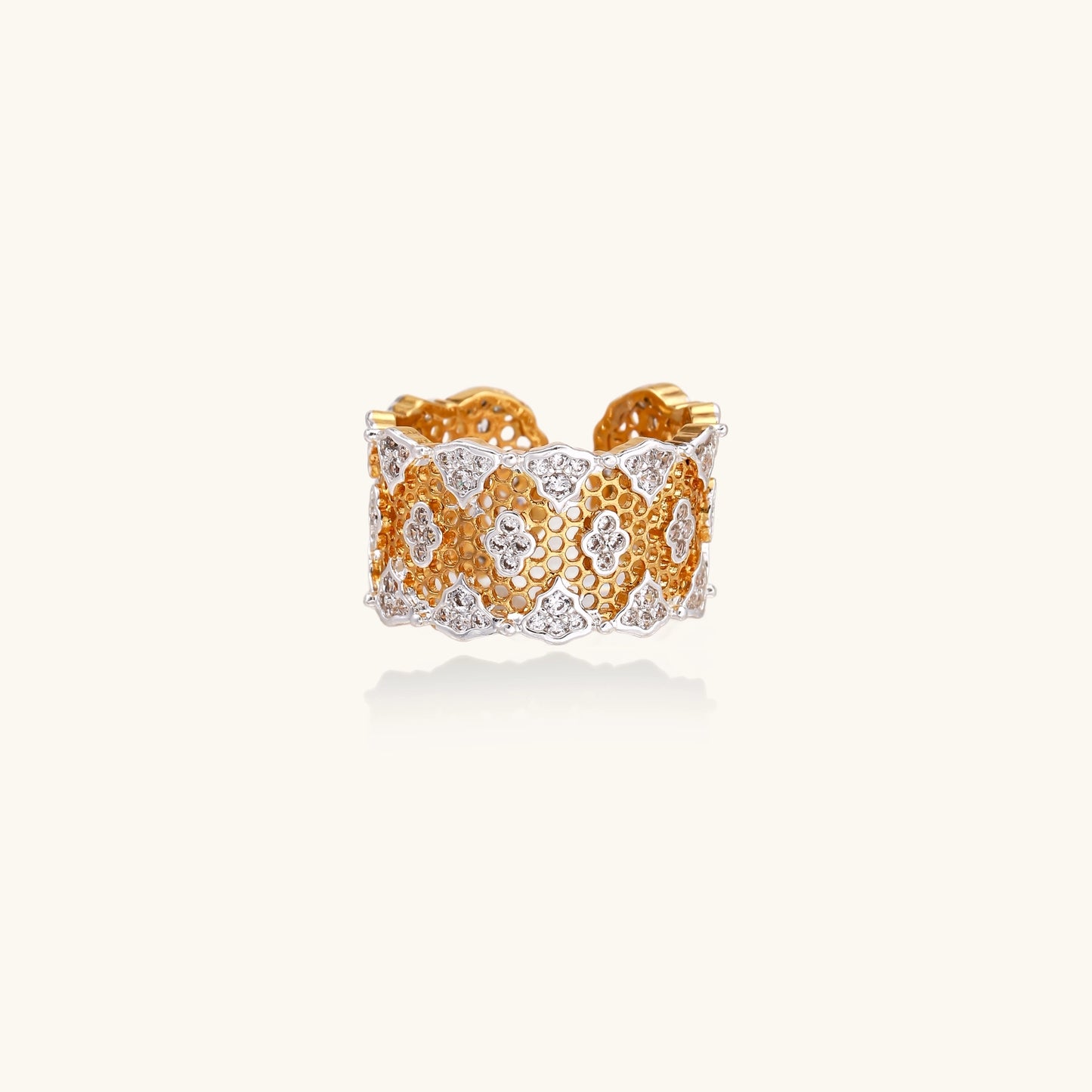 Wide gold-plated ring featuring intricate honeycomb mesh pattern with scattered zirconia stones on cream background