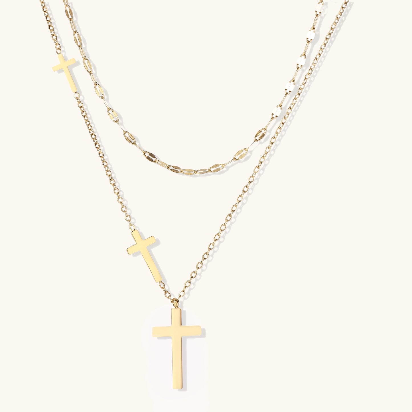 Two layered 14K gold-plated cross necklaces with adjustable chains on light background.