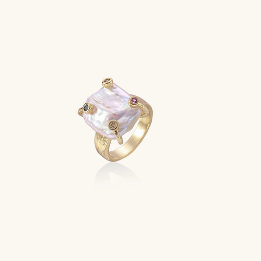 Gold-plated ring featuring large baroque freshwater pearl with small colorful gemstone accents on textured band