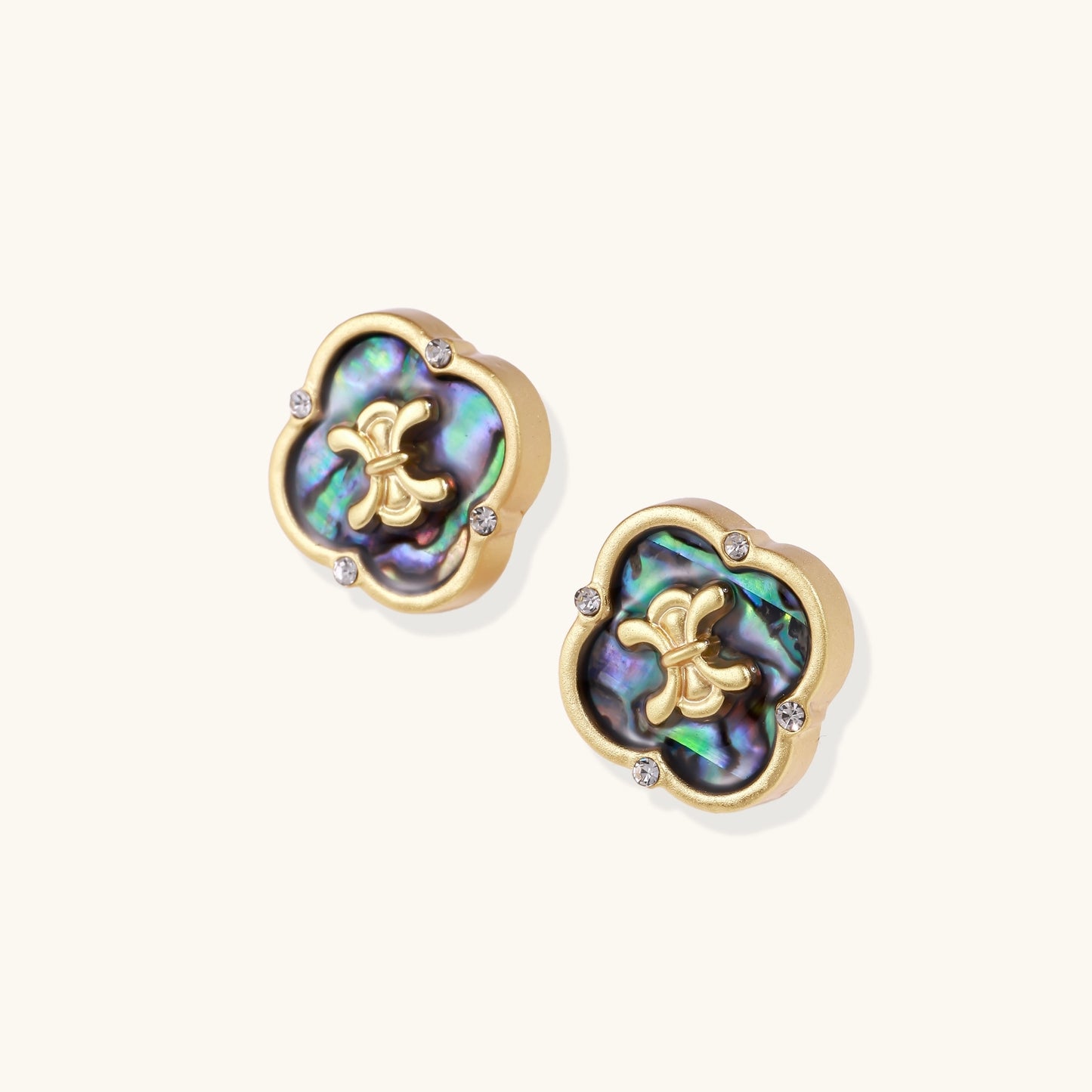 Gold-plated quatrefoil stud earrings featuring iridescent abalone shell centers with decorative motifs and crystal accents