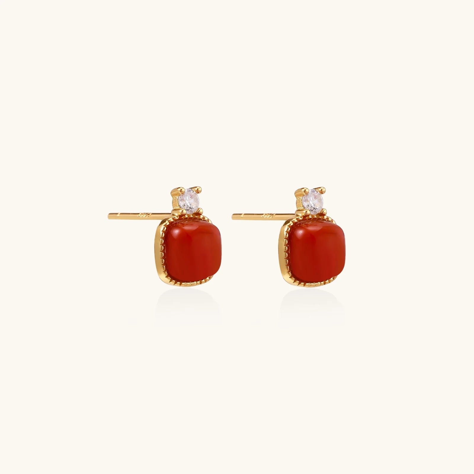 18K gold vermeil stud earrings with cushion-cut red agate stones and sparkling crystal accents on beige background